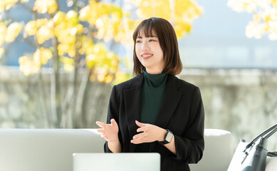 秋のオフィスで対話をする笑顔の女性・ビジネスウーマン