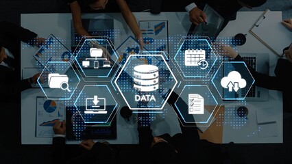 A top-down view of business professionals engaging in strategic discussions around data analytics, emphasizing technology, teamwork, and innovative solutions in an office environment. Raster