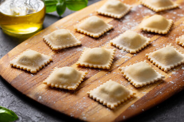 Ravioli on a wooden board. Grey background. Close up.