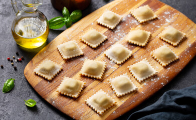 Ravioli on a wooden board. Grey background. Close up.