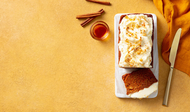 Carrot cake loaf on a white marble board. Yellow background. Copy space. Top view.