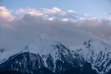 snow covered mountains tatry poland with clouds around and big pine trees
