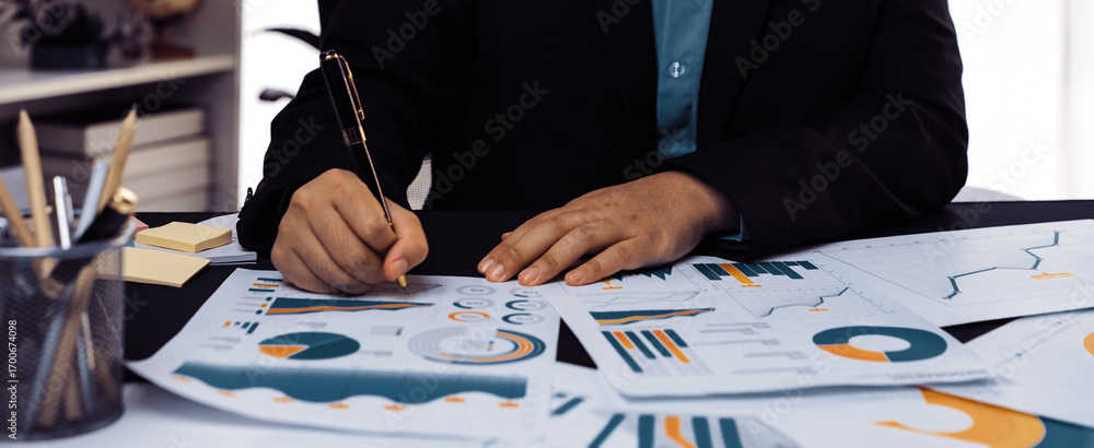 Poster a business professional engaged in a detailed analysis of financial reports and graphs at a modern o