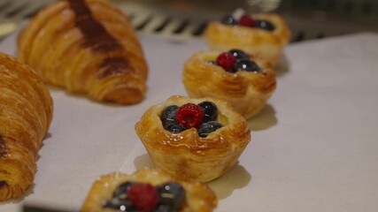 Array of delights including croissants and fruit flans topped with vibrant berries. Close up of bakery tray with fresh pastries. - Powered by Adobe