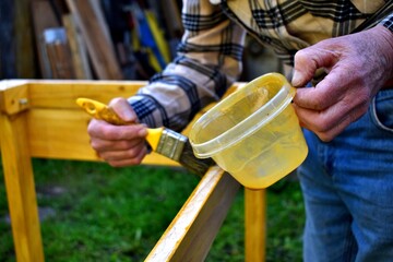 Manos de hombre mayor barnizando madera. 