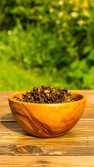 Dried tea leaves in a wooden bowl, outdoors