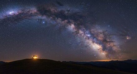 Fototapeta premium Milky Way arches over a solitary hilltop cabin