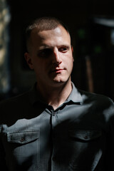Man in a gray shirt illuminated by natural light casting shadows on face