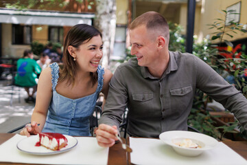 Happy couple enjoying dessert together in a sunny outdoor café garden in summer