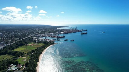 Aerial Port Moresby Coastline Harbor - An aerial view showcases Port Moresby's coastline, featuring a bustling harbor filled with cargo ships and cranes against a backdrop of clear blue ocean and a