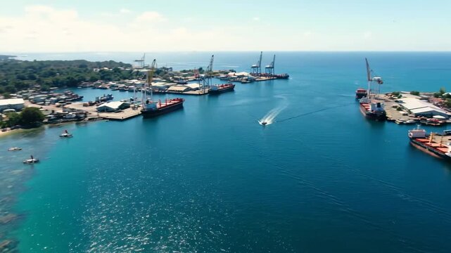 Aerial View of Port Moresby Harbor and Coastline - An aerial shot showcases Port Moresby's harbor, with cargo ships and cranes visible.
