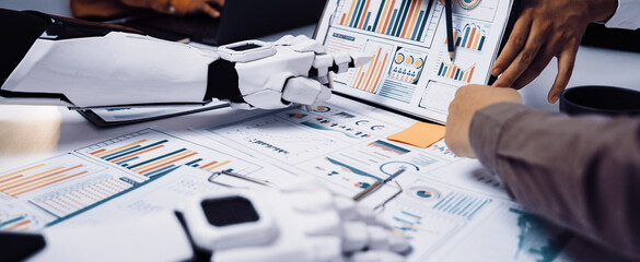 A collaborative scene showing humans and robots working together on data analysis with colorful charts, emphasizing teamwork and innovation in a modern office setting.Noogenesis