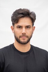 Obraz premium A man with a beard and a black shirt is standing in front of a white background