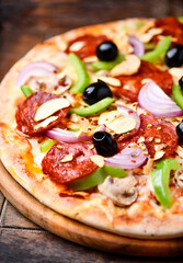 Pizza with chorizo ​​sausage, mozzarella cheese, green pepper and black olives. Rustic wooden background. Soft focus.	