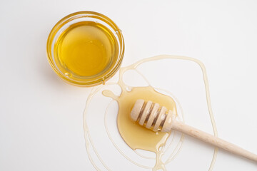 Honey splashes from a wooden dipper  on a white background. Natural product.