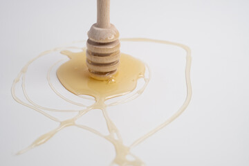 Honey splashes from a wooden dipper  on a white background. Natural product.