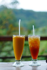 Two vibrant fruit smoothies present themselves, full of color and refreshment on a wooden table.