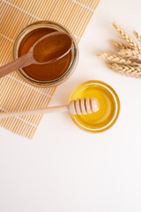 Jar of honey with wooden honey dipper on white kitchen background. Tasty honey bunker.