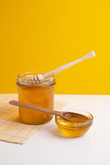 Jar of honey with wooden honey dipper on white kitchen background. Tasty honey bunker.