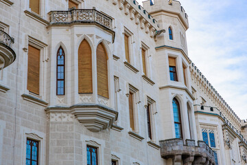 Obraz premium Historic european castle facade with towers and arched windows under blue sky