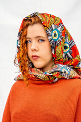 A woman with red hair is wearing a scarf with flowers on it