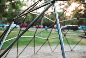 Fototapeta premium Modern metal climbing dome on a playground, geometric jungle gym for children, vibrant outdoor play area, safe climbing structure, active kids having fun in the park