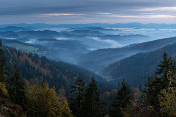 Fototapeta premium Misty mountain landscape at sunrise rolling hills and valleys covered in fog autumn colors in the trees