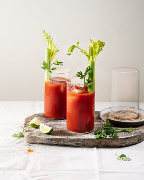 Classic Bloody Mary cocktail served in tall glasses with celery stalks and lime, refreshing brunch drink with tomato juice and ice.