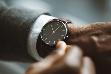 Elegant wristwatch on a man's hand while adjusting time in a professional setting