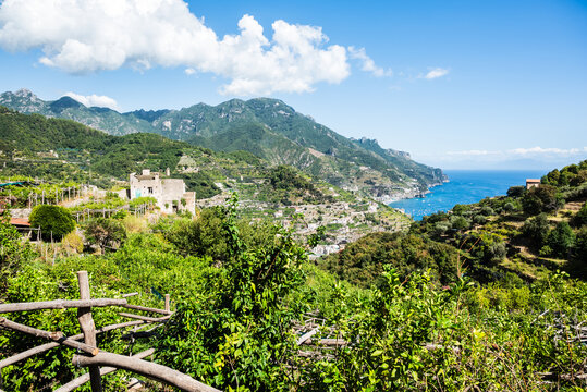 Scenic view of the Amalfi Coast in Italy with lush green hills, Mediterranean vegetation, and the blue Tyrrhenian Sea under a bright summer sky.
