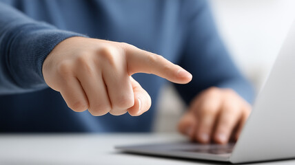 A decisive pointing hand at a laptop signaling selection and accountability, illustrating decision making and user focus in digital interactions.
