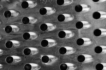 Metal grater with holes. Background and texture. Black and white.