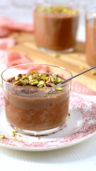A cup of chocolate mousse with pistachios and a spoon