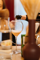 Pouring sparkling wine into a glass during elegant dinner at cozy modern restaurant