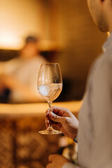 Man holding a glass of sparkling white wine in elegant restaurant interior