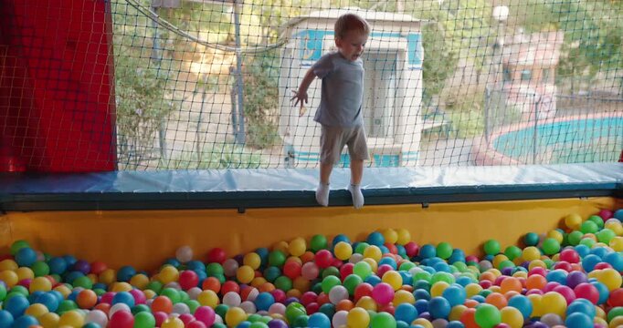 Little boy jumping into the child colorful balls