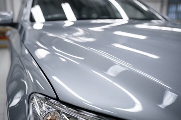 Close-up of a Shiny Silver Automobile Hood Reflecting Overhead Lights
