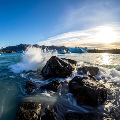 Obraz premium Dramatic waves crash against dark volcanic rocks, revealing turquoise glacial water and icebergs, bathed in the golden light of the setting sun.