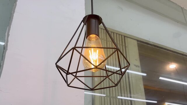 Stylish industrial hanging light fixture with glowing Edison bulb in a modern interior setting