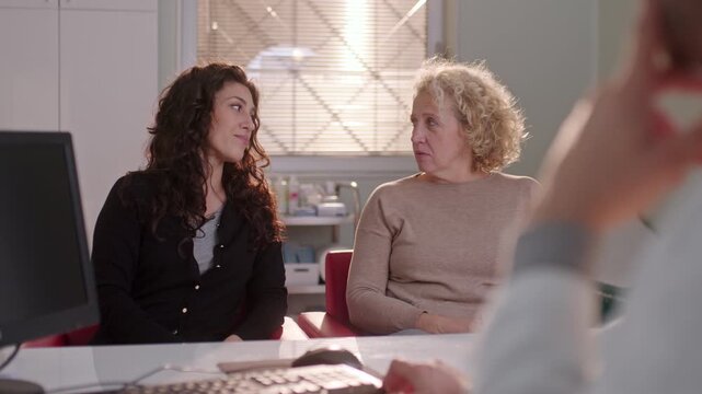 Two women meet with a doctor, engaged in a health consultation indoors, listening intently to advice.