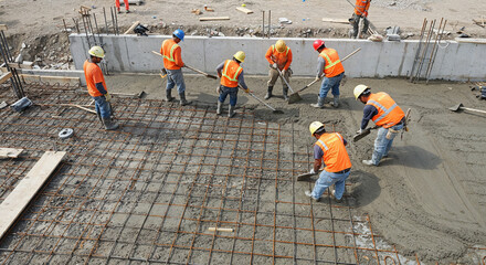 Aerial view of construction workers smoothing cement over rebar
