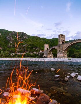 A campfire near a historic stone bridge