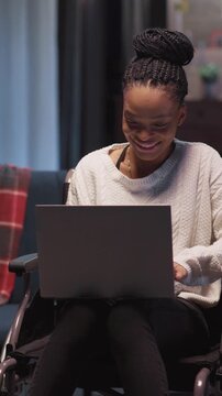 A woman in a wheelchair is conveniently using a laptop computer