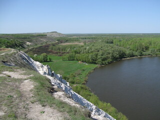Scenic river view with lush greenery and cliff under blue sky  