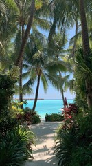 A tranquil tropical pathway leads to a turquoise ocean, framed by lush greenery and swaying palm trees.