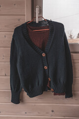 Hand-knitted things. Knitted cardigan. Warm things. Autumn wardrobe. Woolen products. Woolen sweater. Clothes on a hanger. Women's room. Home needlework. Handmade clothes.