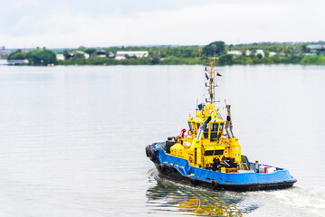 Tug boat sailing through the river near sea port terminal in Buenaventura, Colombia.