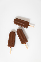 Chocolate ice cream popsicles on white background. Minimalist summer dessert concept