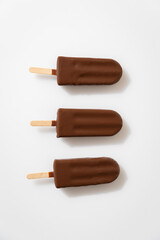 Chocolate ice cream popsicles on white background. Minimalist summer dessert concept