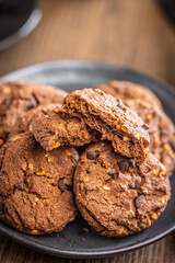 Sweet chocolate cookies on plate on wooden table.